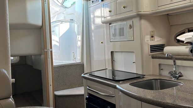 A compact kitchen with a sink, stove, and storage cabinets.