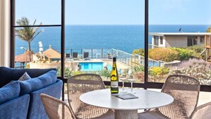 A balcony with a view of the ocean, a pool, and a building in the background. - Breathtaking Clifftop Ocean Views in Eden - Unit 12 Bob and Zita’s escape (Eden)