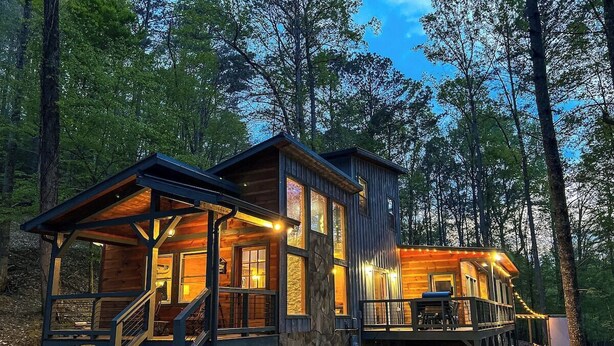 A cabin with a wooden exterior, a deck, and a staircase leading to the entrance. - North GA Relaxing Chic Cabin w/ Resort Amenities (Ellijay)