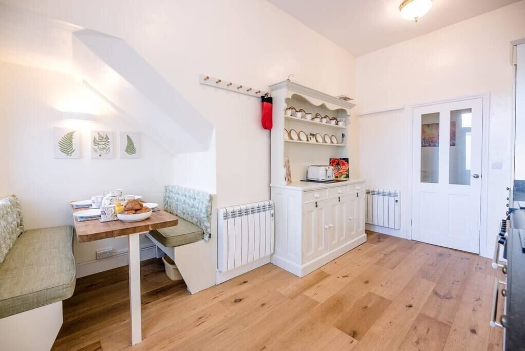 Une cuisine compacte avec un coin repas, des meubles blancs et un radiateur.