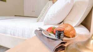 A neatly made bed with white linens, a plate with a croissant, strawberries, and a jar of chocolate spread. - No 12. Southwold (Southwold)