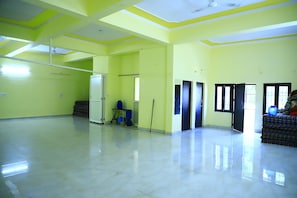 A spacious room with a high ceiling, a door leading to another room, and a window allowing natural light. - Shivraj Homestay (Mathura)