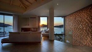 Een moderne woonkamer met een ruime bank, een eethoek en uitzicht op zee.