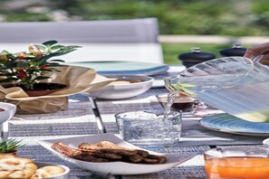 A table set outdoors with plates, bowls, and a pitcher of water. - Panoramic Sea Views to Spinalong Island with a heated pool (Elounda)