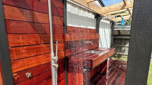 A wooden deck with a built-in shower and a bench. - Newly Renovated Hamptons-Style Beach House - Includes Linen & EV Charger! (Coronet Bay)
