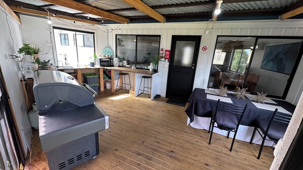 A spacious room with a wooden floor, a kitchen area with a counter and stools, and a dining area with a table and chairs.
