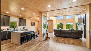 A spacious kitchen with a large island, dark cabinets, and a view of the outdoors through large windows. - Spacious & Upscale with 7 Person Hot Tub, Theater, Views, Game Room, Sauna (Sevierville)