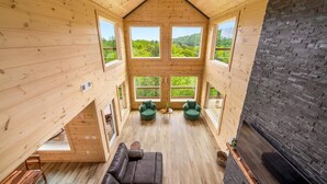A spacious wooden cabin with large windows offering views of a forested landscape. - Spacious & Upscale with 7 Person Hot Tub, Theater, Views, Game Room, Sauna (Sevierville)