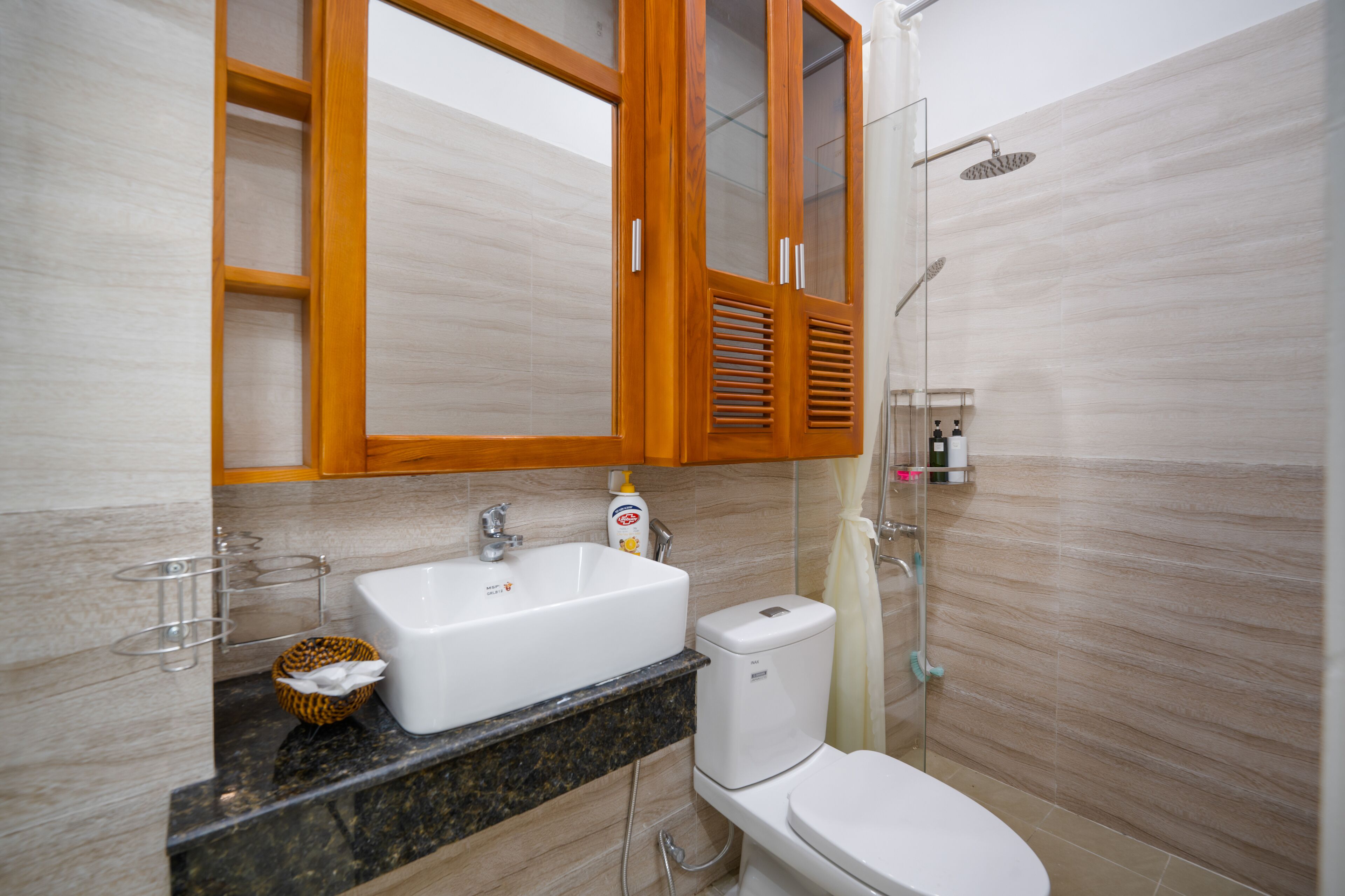 Ein Badezimmer mit Holzwaschtisch, einem weißen Waschbecken, einer Toilette und einer Dusche.