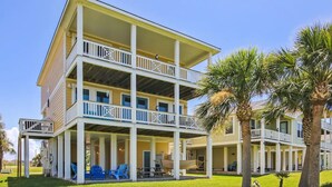 A multi-story hotel with balconies, outdoor seating, and palm trees.