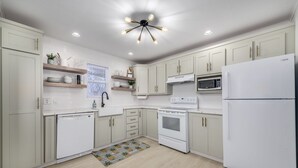Una cocina moderna con armarios blancos, un microondas, una estufa y un refrigerador.