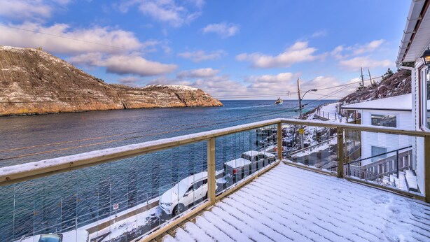 Una cubierta nevada con vistas al mar tranquilo y acantilados rocosos.