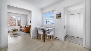Una sala moderna con comedor, un sofá de cuero marrón, una mesa de comedor con sillas y vistas a un paisaje rocoso a través de una ventana.