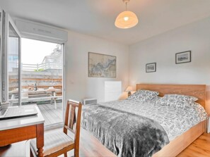 Une chambre à coucher avec un lit, un bureau et une chaise. Il y a une fenêtre donnant sur un balcon.