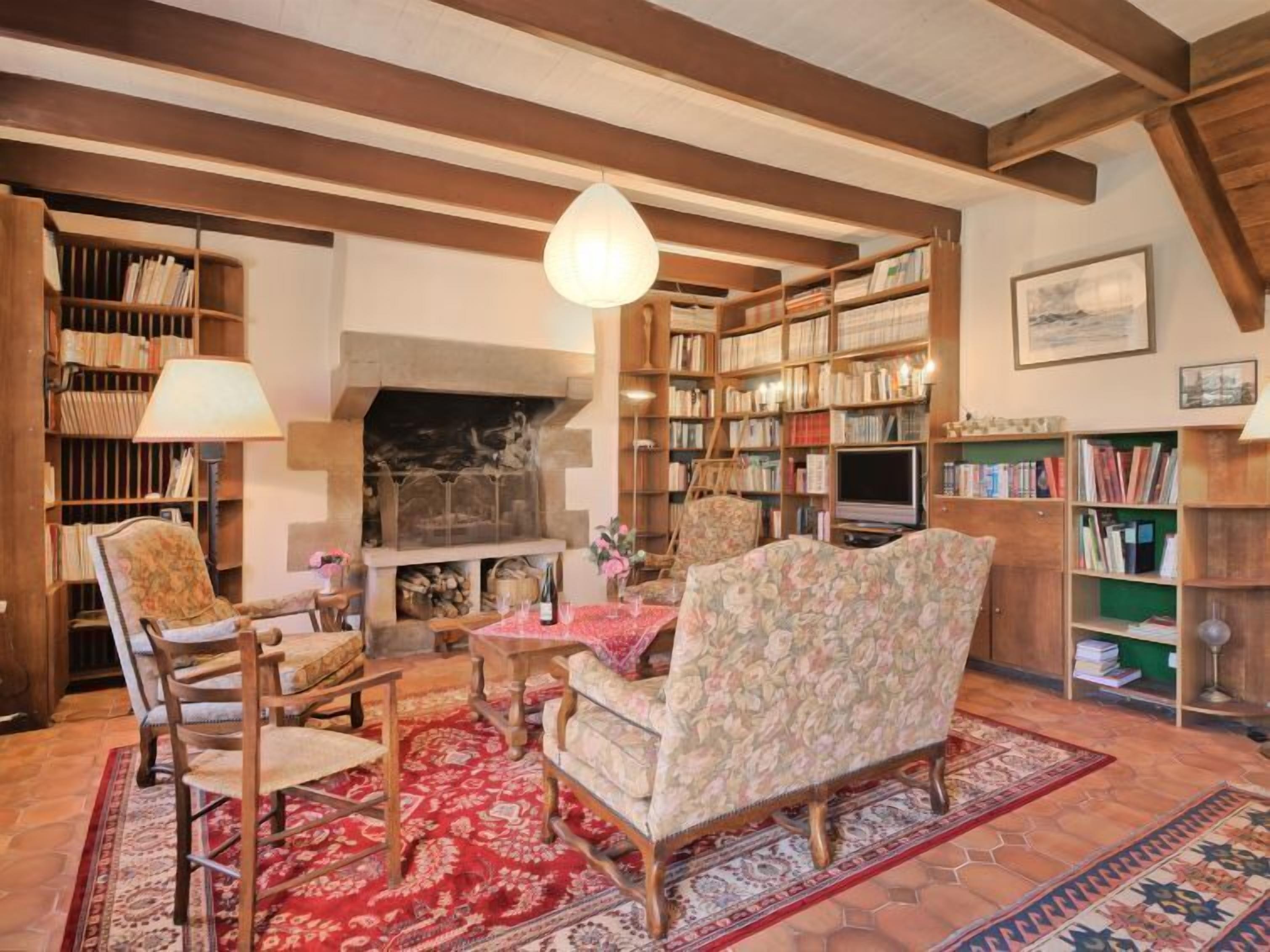 A cozy living room with a fireplace, wooden bookshelves, and comfortable seating.