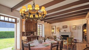 A dining area with a checkered tablecloth, wooden chairs, a chandelier, and a fireplace. - Ker Vignan by Interhome (Ile Grande)