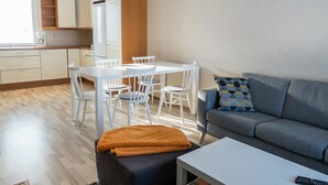 A modern living room with a grey sofa, a white coffee table, and a dining area with a white table and chairs.