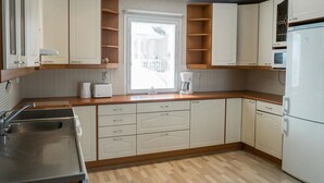 A compact kitchen with white cabinets, a built-in microwave, and a window with blinds.