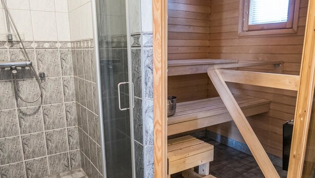 A wooden cabin with a shower area and a wooden bench.