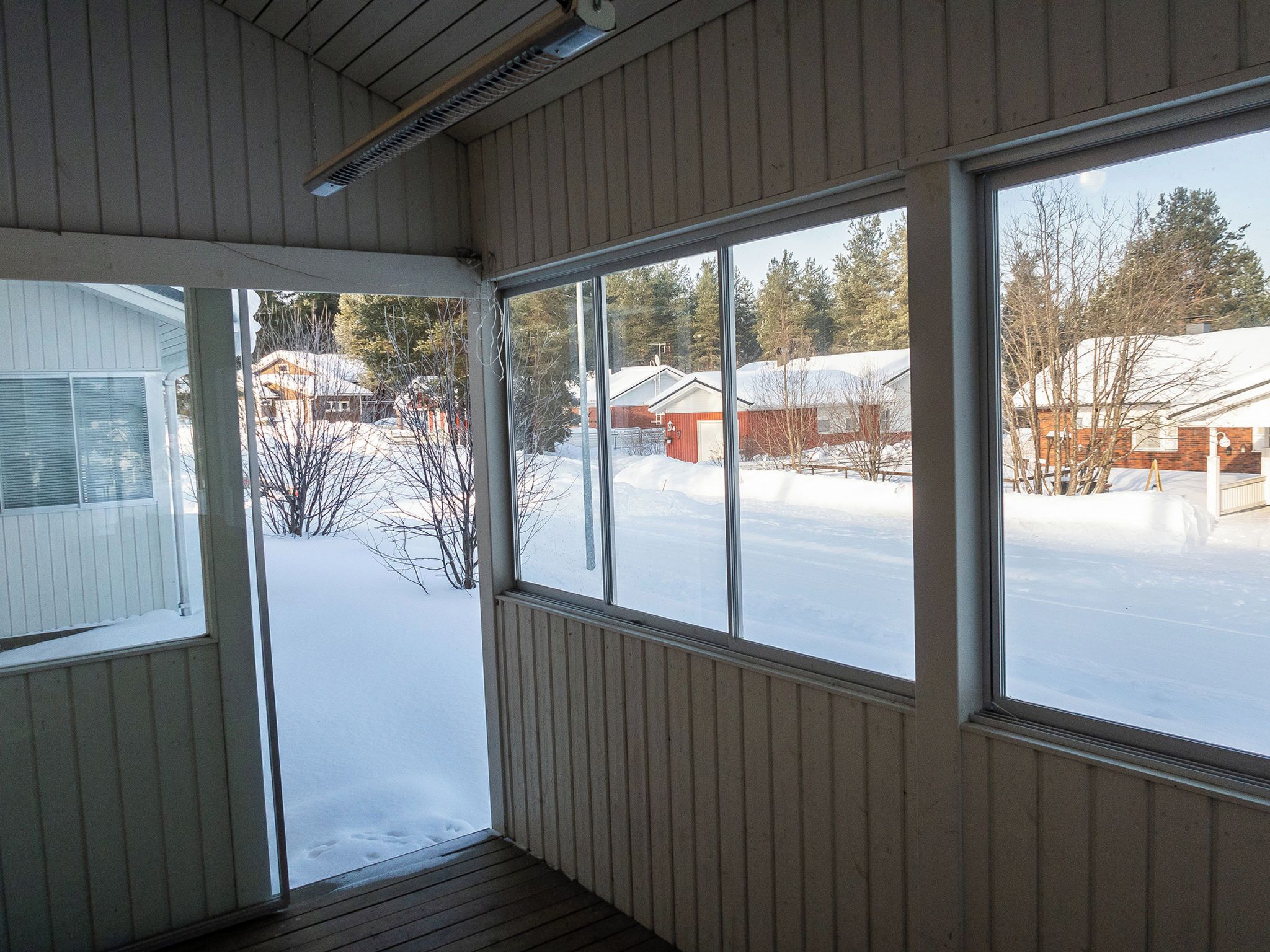 Ein Zimmer mit großen Fenstern mit Blick auf eine verschneite Landschaft und Häuser.