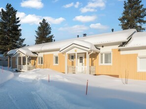 Une rangée de bâtiments à un seul étage, dont les toits sont recouverts de neige, sous un ciel dégagé.
