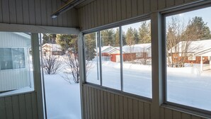A room with large windows overlooking a snowy landscape, featuring a wooden floor and a visible radiator.