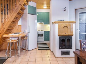 Une cuisine compacte avec un escalier en bois, un coin repas doté de tabourets de bar et un four encastré.