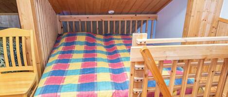 Una cama litera de madera con una colcha de cuadros coloridos y un cabecero de madera.