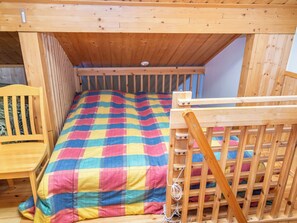 A wooden bunk bed with a colorful checkered bedspread and a wooden headboard. - Tahkon alppitalo 4 as. 3 by Interhome (Lapinlahti)