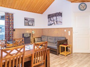 Una habitación acogedora con techo de madera, un sofá, una mesa de comedor con sillas y una mesita auxiliar.