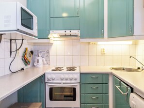 Une cuisine avec des meubles de couleur turquoise, une cuisinière blanche et un four à micro-ondes.