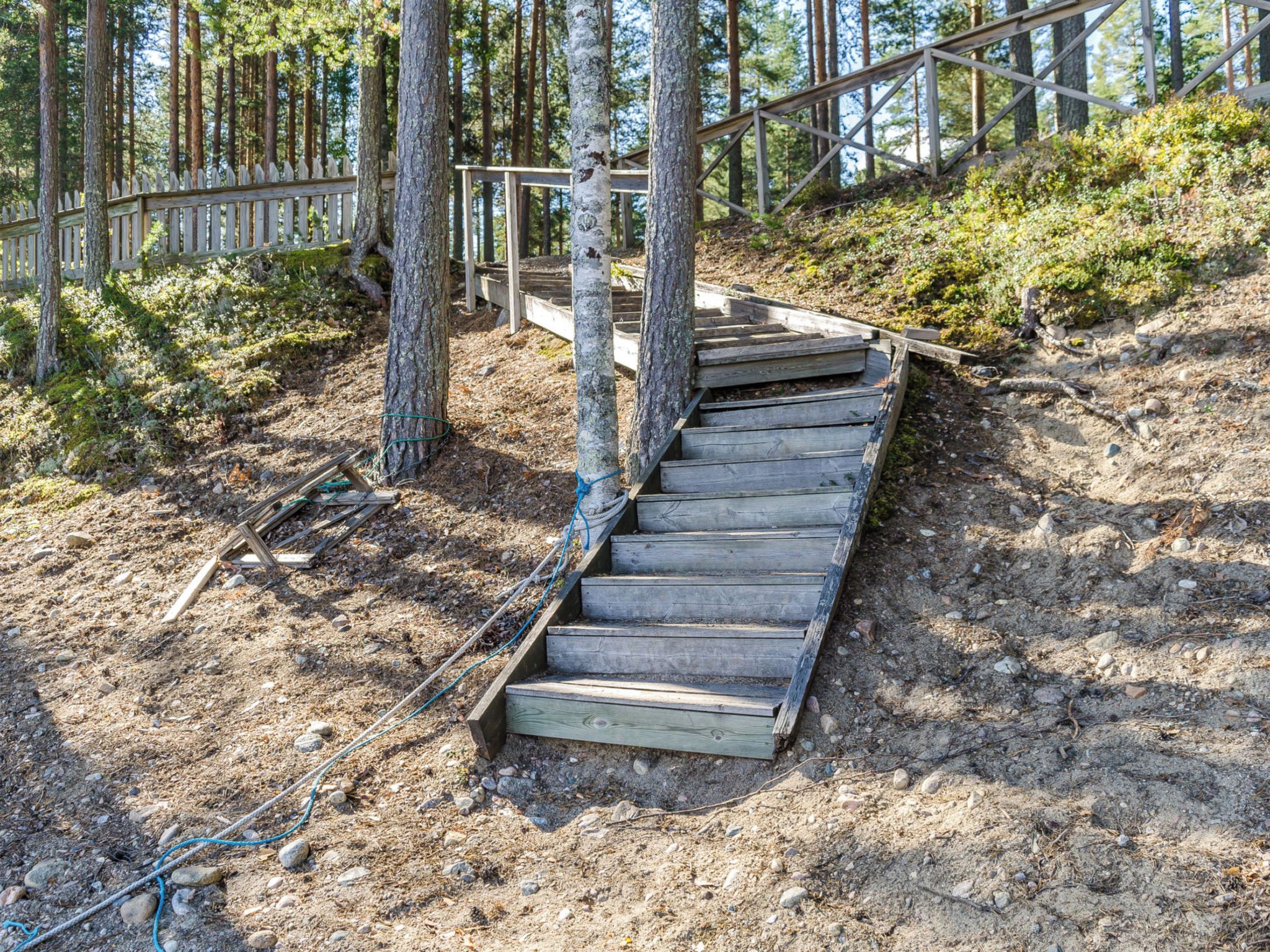 A wooden staircase in a forested area with a wooden fence and trees.