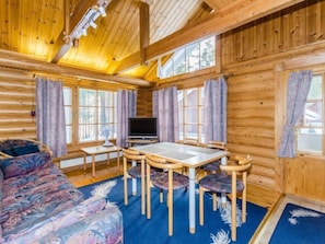 Relax in this cabin with a comfortable sofa, dining table, and sloped ceiling.