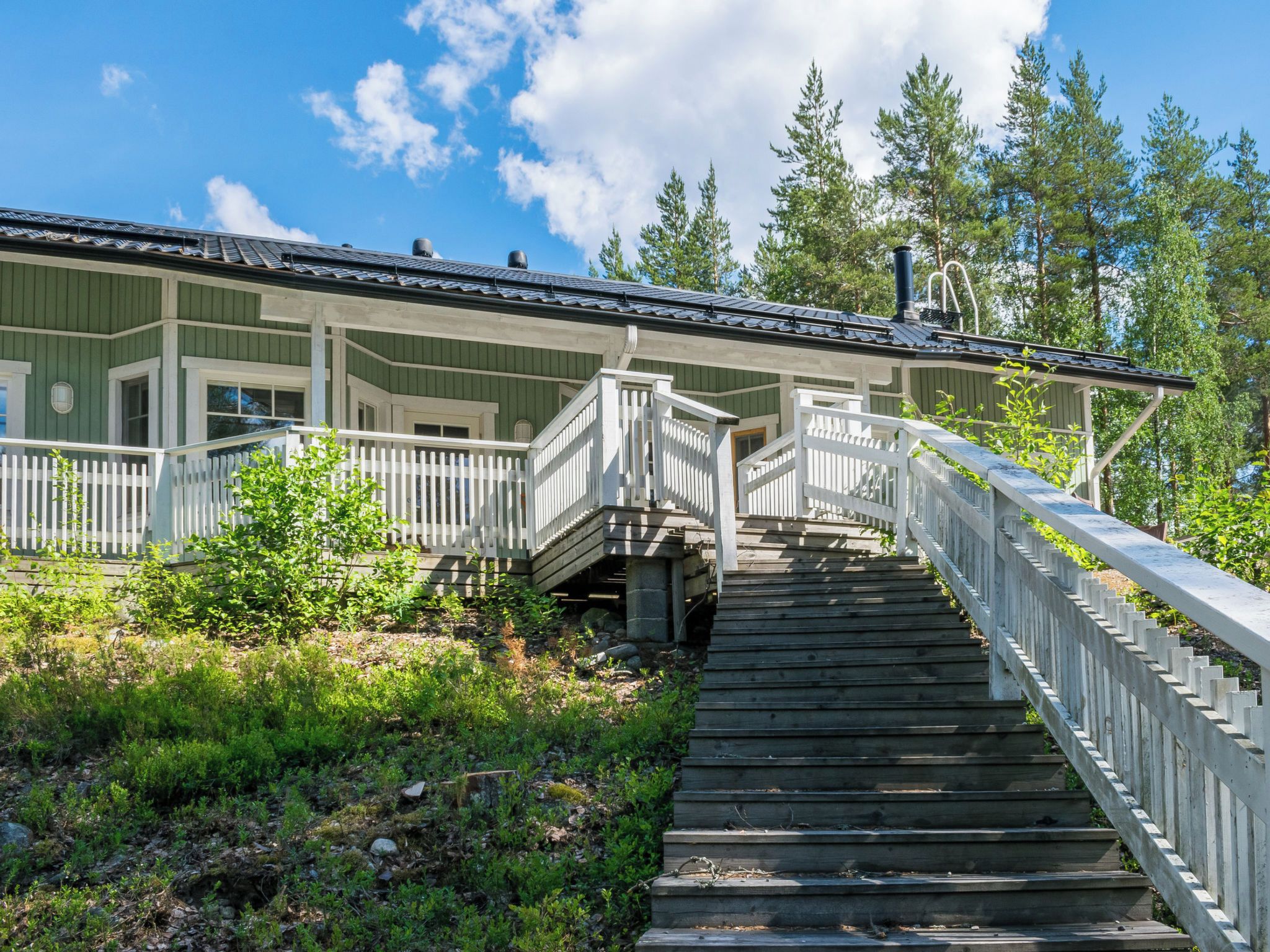 A wooden staircase leading to a building with a white railing and a covered porch.