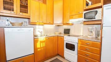 A compact kitchen with wooden cabinets, a built-in microwave, a stove, and a refrigerator.