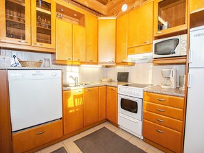 A compact kitchen with wooden cabinets, a built-in microwave, a stove, and a refrigerator.