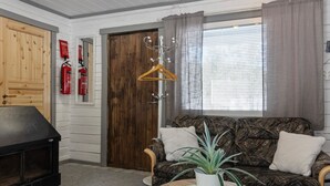 Ein gemütliches Wohnzimmer mit einer Couch, einem kleinen Tisch mit Pflanze, einem Kleiderständer und einer Holztür.