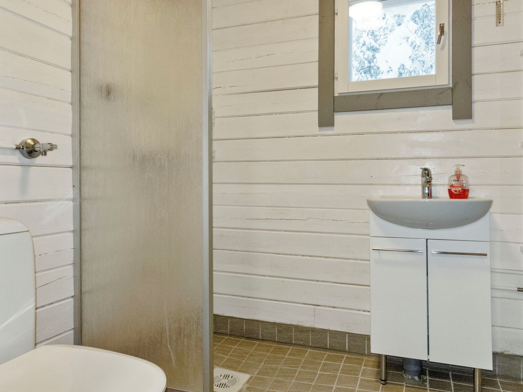 Ein Badezimmer mit einem weißen Waschbecken, einem Spiegel darüber und einer Duschkabine.