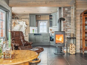 Ein gemütliches Wohnzimmer mit einem Ledersofa, einem Holztisch und einem Kamin aus Stein.