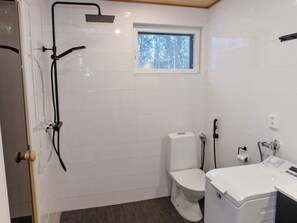 Uma casa de banho moderna com chuveiro, sanita e lavatório.