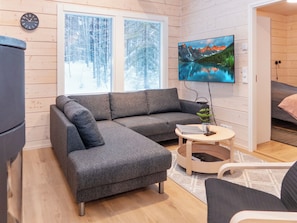 Una sala de estar moderna con un sofá modular, una mesita redonda y un televisor montado en la pared.