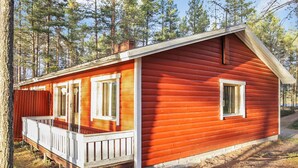A red wooden cabin with a porch, surrounded by trees. - Mäkitupa 1 by Interhome (Kuusamo)