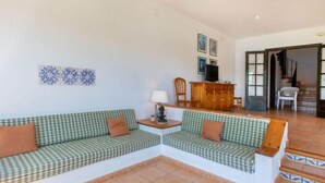A living room with a checkered sofa, a wooden cabinet, and a television.