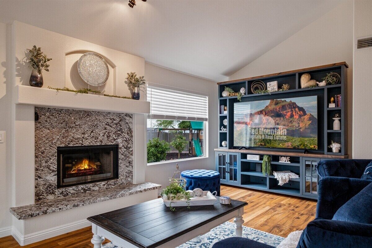 A living room with a stone fireplace, a television, and a blue sofa.