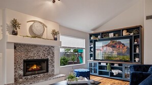 Een woonkamer met een stenen openhaard, een televisie en een blauwe bank.