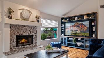 A living room with a stone fireplace, a television, and a blue sofa.