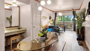 A modern interior with a glass dining table, wooden bench, and a seating area with chairs. - Designer Corner Suite 3br/2ba - Disney & Universal (Orlando)