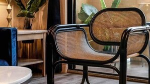 A modern room with a large window, a wicker chair, a small table, and a lamp. - Designer Corner Suite 3br/2ba - Disney & Universal (Orlando)