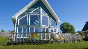 A two-story house with a large bay window, a balcony, and a fenced yard.