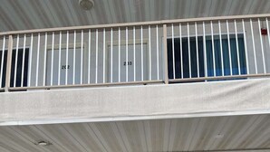 Un bâtiment doté d’un toit plat, de trois portes bleues et d’un balcon avec des balustrades blanches.